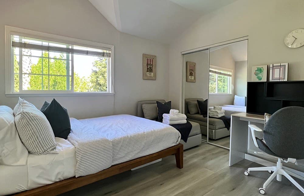 West room: twin bed, desk, sitting area and mirrored closet