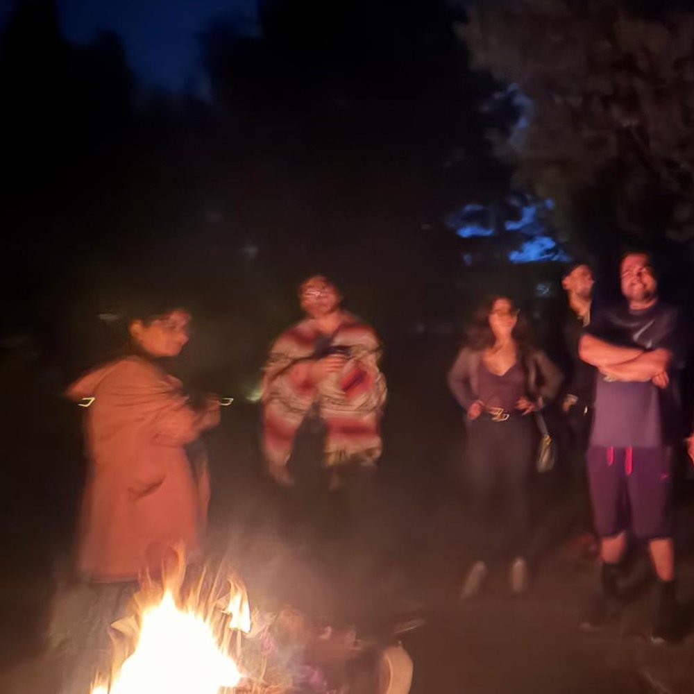Guests standing around the fire at nightfall
